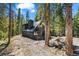 Beautiful log cabin with metal roof and porch nestled among tall pine trees on a sunny day at 46 Silver Creek Rd, Idaho Springs, CO 80452
