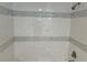 Close up of the tiled tub and shower featuring a decorative gray tile at 805 Park Ave, Fort Lupton, CO 80621