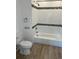 Bathroom with tiled bathtub, featuring tiled walls, a toilet, and wood-look flooring at 805 Park Ave, Fort Lupton, CO 80621