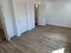 A bedroom with wood-look flooring, white walls, and multiple doors at 805 Park Ave, Fort Lupton, CO 80621