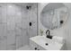 Bright bathroom featuring a tiled shower with black matte fixtures and a modern vanity with round mirror at 141 S Knox Ct, Denver, CO 80219