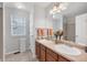 Bright bathroom featuring a double vanity, large mirror, and window at 9272 Melborne Ct, Parker, CO 80134