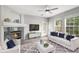 Bright living room with a modern ceiling fan, a corner fireplace, and a white sofa with blue accent pillows at 3952 S Carson St # 103, Aurora, CO 80014
