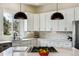 Bright kitchen features white cabinets, marble backsplash, stainless steel appliances, and black pendant lighting at 598 Stonemont Dr, Castle Pines, CO 80108