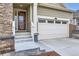 Home's front entryway with a two-car garage, featuring stone details and an inviting entrance at 15211 Quince St, Thornton, CO 80602
