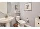 Powder room features a pedestal sink, toilet, and decorative wall art at 15211 Quince St, Thornton, CO 80602