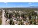 Wide aerial view showcases the expansive landscape, forests, and distant mountains, under a bright blue sky with scattered clouds at 2859 Cagle Dr, Larkspur, CO 80118