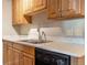 This updated kitchen features wood cabinetry, a black dishwasher, stainless steel sink, and a light countertop at 10792 E Exposition Ave # 154, Aurora, CO 80012
