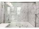 A glass-enclosed tub/shower with marble-style tile features jets in the tub and a handheld shower wand at 2501 15Th St # 2C, Denver, CO 80211