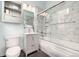 Cozy bathroom featuring a vanity, mirror, and toilet next to a shower/tub with glass doors and marble style tiling at 2501 15Th St # 2C, Denver, CO 80211