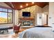 Inviting bedroom showcasing a stone fireplace, wood ceiling, and scenic views from a large window at 77 Comstock Pl, Castle Rock, CO 80108
