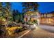 Majestic home exterior featuring a stone driveway, lush landscaping, and elegant water feature at night at 77 Comstock Pl, Castle Rock, CO 80108