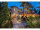 Stunning brick home with a stone pathway and lush landscaping, illuminated for a warm evening ambiance at 77 Comstock Pl, Castle Rock, CO 80108