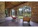 Covered stone patio with arched openings, featuring comfortable seating and views of the landscaped grounds at 77 Comstock Pl, Castle Rock, CO 80108