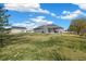Spacious backyard with a well-maintained lawn, white fencing, barn, and mature trees at 56330 E 37Th Ct, Strasburg, CO 80136