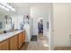 Bright bathroom featuring double sinks, a large mirror, a walk-in shower, and a closet at 56330 E 37Th Ct, Strasburg, CO 80136