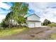 Side view of the two-story white home with an attached garage and a green yard with mature trees at 43388 Somerset Ct, Elizabeth, CO 80107