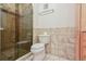 Well-lit bathroom featuring tiled shower with glass door, tiled walls, and a modern toilet at 534 E 7Th Ave # 107, Denver, CO 80203