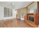Open living room featuring wood floors, built-in shelving, and a cozy brick fireplace at 534 E 7Th Ave # 107, Denver, CO 80203