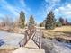 A walking bridge crosses a partially frozen creek under a bright blue sky with clouds and mature trees at 5920 S Bemis St, Littleton, CO 80120