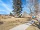 Sidewalks cross through a grassy park with mature trees, landscaping, and community signage at 5920 S Bemis St, Littleton, CO 80120