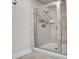 Shower featuring neutral tiling, a shower caddy, and a glass door at 5920 S Bemis St, Littleton, CO 80120