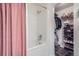 Bright white bathroom and shower with rod and a closet with shoe and bag storage at 11832 Zenobia Loop, Westminster, CO 80031