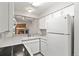 Bright kitchen with white cabinets, modern appliances, and a view of the cozy fireplace in the living area at 8879 W Floyd Ave, Lakewood, CO 80227