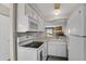 Efficient kitchen equipped with white appliances, ample cabinetry, and a cozy eat-in area at 8879 W Floyd Ave, Lakewood, CO 80227