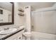 Bathroom featuring a shower over tub with glass doors, toilet, and sink with a large mirror at 6494 W 85Th Ave, Arvada, CO 80003