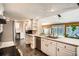 Well-lit kitchen featuring white cabinets, stone countertops, modern appliances, and an adjacent breakfast nook at 6494 W 85Th Ave, Arvada, CO 80003