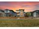 Stylish two-story home at sunset, showcasing a stone facade, balcony, and beautifully landscaped front yard at 6054 N Perth St, Aurora, CO 80019