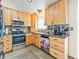 Well-lit kitchen featuring light wood cabinets, tile floors, backsplash, and stainless steel appliances at 4182 S Bahama St, Aurora, CO 80013
