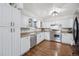 White kitchen with stainless steel appliances and wood floors at 7636 S Eaton Way, Littleton, CO 80128