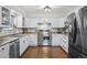 White kitchen with stainless steel appliances and wood floors at 7636 S Eaton Way, Littleton, CO 80128