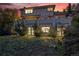 The back of a home features a patio at sunset and illuminated windows at 5855 Saddle Creek Trl, Parker, CO 80134