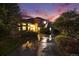 Charming home with lush landscaping and a long driveway; outdoor lighting enhances the curb appeal under a colorful sunset at 5855 Saddle Creek Trl, Parker, CO 80134