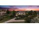 Expansive home with mature trees, lush landscaping and a circular driveway under a gorgeous, colorful sunset at 5855 Saddle Creek Trl, Parker, CO 80134