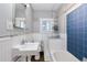 Bathroom featuring white wainscoting, a sink, toilet, and a blue-tiled bathtub at 3336 N Saint Paul St, Denver, CO 80205