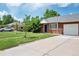 Brick home exterior with well-maintained lawn, driveway, and mature trees at 6765 W 33Rd Ave, Wheat Ridge, CO 80033