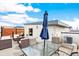 Stylish rooftop deck with comfortable wicker seating, a glass table, and an umbrella for shade on a sunny day at 2726 Federal Blvd # 1, Denver, CO 80211