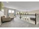 Comfortable loft with chair, carpeting and views of the living area, large windows, and spindle staircase at 7472 S Utica St, Littleton, CO 80128