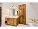 A bathroom with a wooden vanity, a sink, a mirror, and lighting fixtures, next to a shower tub at 8159 Lodgepole Trl, Lone Tree, CO 80124