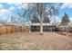 Large backyard with a tall tree and an enclosed sunroom attached to the house at 1575 Verbena St, Denver, CO 80220