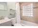 A bright bathroom featuring a glass block window, floating shelves, and a shower-tub combo at 1575 Verbena St, Denver, CO 80220
