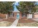 Charming brick home featuring a blue door with a wreath, a well-maintained yard, and lush greenery at 1575 Verbena St, Denver, CO 80220