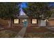 Charming brick home featuring a blue door with a wreath, a well-maintained yard, and lush greenery at 1575 Verbena St, Denver, CO 80220