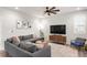 Cozy living room with gray sectional, ceiling fan, stylish decor, and a media center for relaxation at 1845 Meagan Way, Erie, CO 80516