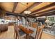Open-concept dining room with wood beams, a dining table, and views into the kitchen and living room at 32462 Lodgepole Dr, Evergreen, CO 80439