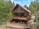 Stunning exterior view of a brown two-story home surrounded by lush trees, featuring multiple decks and outdoor living spaces at 32462 Lodgepole Dr, Evergreen, CO 80439